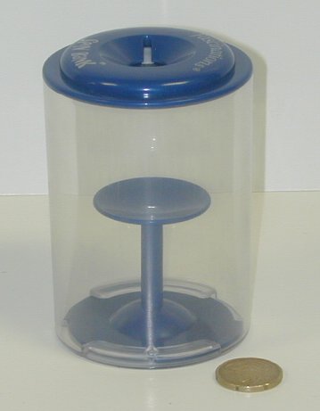 La hucha vacía, con una moneda al lado para dar idea del tamaño.